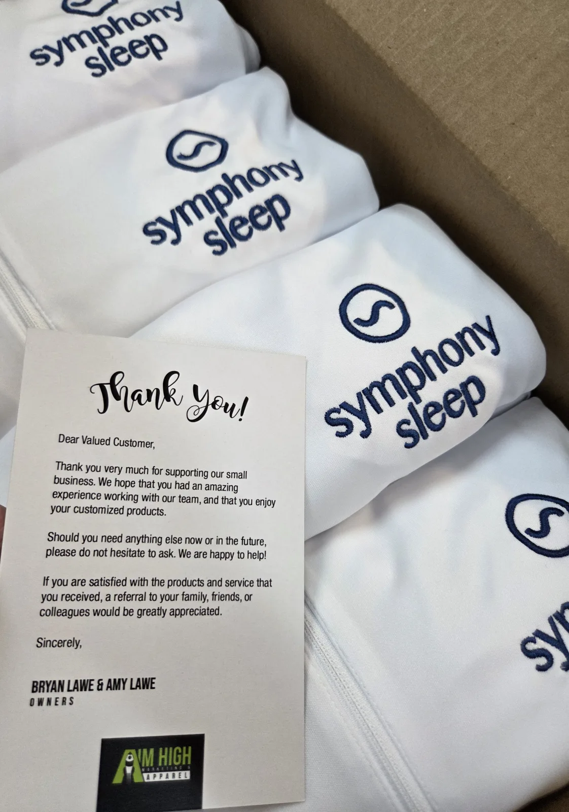 Folded custom apparel order for Symphony Sleep with an Aim High thank-you card